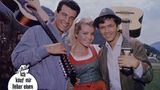 Hannelore Auer steht zwischen zwei Männern mit Gitarre