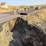 Neben einer Straße hat sich ein großes Loch in der Erde aufgetan.