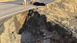 Neben einer Straße hat sich ein großes Loch in der Erde aufgetan.