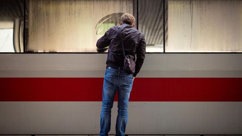 Ein Mann schaut in einen am Bahnsteig stehenden ICE