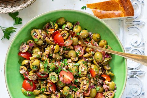 Bazrkani   Armenischer Olivensalat  Für 4 Portionen  Zutaten:  200 g entsteinte grüne Oliven 1 rote Zwiebel  5–10 Cherrytomaten  2 EL Tomatenmark  1 EL Granatapfelsirup/Granatapfelkonzentrat (alternativ Balsamico-Essig oder Balsamico-Creme)  2 EL Olivenöl  1⁄2 TL schwarzer Pfeffer aus der Mühle  1⁄2 TL edelsüßes Paprikapul- ver  1 Prise Kreuzkümmel 1⁄2 TL getr. Thymian  1⁄2 Bund Petersilie 50 g Walnusskerne Salz nach Bedarf     Zubereitung:  1. Oliven längs halbieren oder vierteln. Zwiebel schälen und fein würfeln. Tomaten waschen, trocken tupfen und vierteln. Alles in einer Schüssel miteinander vermengen.  2. Für das Dressing Tomatenmark, Granatapfelsirup und Olivenöl miteinander vermischen, bei Bedarf 1 TL Wasser hinzufügen und glattrühren. Mit Pfeffer, Paprikapulver, Kreuzkümmel und Thymian abschmecken. Dressing zum Salat geben und alles gut vermengen. Einige Minuten ziehen lassen.  3. Währenddessen Petersilie waschen, trocken schütteln und fein hacken. Walnusskerne ebenfalls hacken. Petersilie und Walnusskerne zum Salat geben und vermengen.  4. Probieren und bei Bedarf salzen (meist reicht jedoch der Salzgehalt der Oliven aus). Sofort servieren oder im Kühlschrank eine halbe Stunde ziehen lassen.     »Bazrkani« stammt aus den Dörfern der Region Musa Ler (heutige Türkei), wo im ehemaligen Osmanischen Reich überwiegend armenische Menschen lebten und den fruchtbaren Boden und das günstige Klima für die Landwirtschaft nutzten. Der Oliven- salat Bazrkani wird auch »Hirtensalat aus Musa Ler« genannt. Die Schafhirten konnten ihn mit nur wenigen Zutaten auch draußen bei ihrer Herde zubereiten. Anfang des 20. Jahrhunderts brachten armenische Überlebende des Genozids dieses Gericht schließlich in ihre neue Heimat, die Republik Armenien.