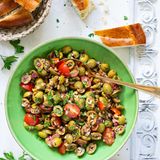 Bazrkani   Armenischer Olivensalat  Für 4 Portionen  Zutaten:  200 g entsteinte grüne Oliven 1 rote Zwiebel  5–10 Cherrytomaten  2 EL Tomatenmark  1 EL Granatapfelsirup/Granatapfelkonzentrat (alternativ Balsamico-Essig oder Balsamico-Creme)  2 EL Olivenöl  1⁄2 TL schwarzer Pfeffer aus der Mühle  1⁄2 TL edelsüßes Paprikapul- ver  1 Prise Kreuzkümmel 1⁄2 TL getr. Thymian  1⁄2 Bund Petersilie 50 g Walnusskerne Salz nach Bedarf     Zubereitung:  1. Oliven längs halbieren oder vierteln. Zwiebel schälen und fein würfeln. Tomaten waschen, trocken tupfen und vierteln. Alles in einer Schüssel miteinander vermengen.  2. Für das Dressing Tomatenmark, Granatapfelsirup und Olivenöl miteinander vermischen, bei Bedarf 1 TL Wasser hinzufügen und glattrühren. Mit Pfeffer, Paprikapulver, Kreuzkümmel und Thymian abschmecken. Dressing zum Salat geben und alles gut vermengen. Einige Minuten ziehen lassen.  3. Währenddessen Petersilie waschen, trocken schütteln und fein hacken. Walnusskerne ebenfalls hacken. Petersilie und Walnusskerne zum Salat geben und vermengen.  4. Probieren und bei Bedarf salzen (meist reicht jedoch der Salzgehalt der Oliven aus). Sofort servieren oder im Kühlschrank eine halbe Stunde ziehen lassen.     »Bazrkani« stammt aus den Dörfern der Region Musa Ler (heutige Türkei), wo im ehemaligen Osmanischen Reich überwiegend armenische Menschen lebten und den fruchtbaren Boden und das günstige Klima für die Landwirtschaft nutzten. Der Oliven- salat Bazrkani wird auch »Hirtensalat aus Musa Ler« genannt. Die Schafhirten konnten ihn mit nur wenigen Zutaten auch draußen bei ihrer Herde zubereiten. Anfang des 20. Jahrhunderts brachten armenische Überlebende des Genozids dieses Gericht schließlich in ihre neue Heimat, die Republik Armenien.