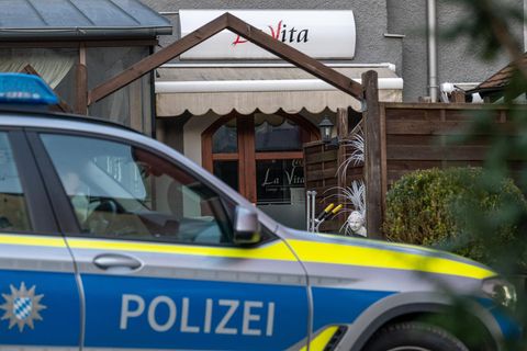 Ein Auto der Polizei Bayern steht vor einem Lokal