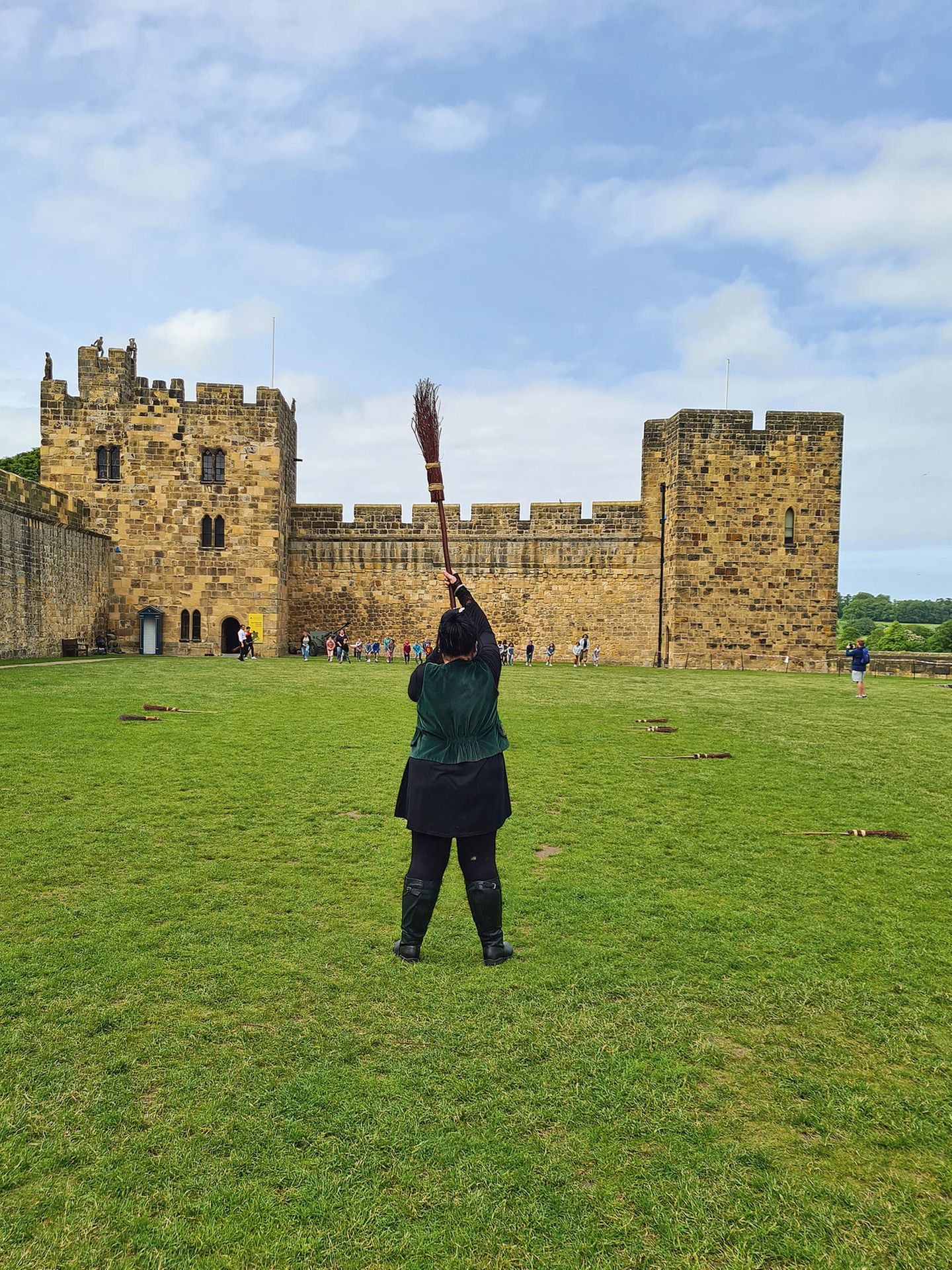 Alnwick Castle – Besenflugtraining Alnwick Castle, eine Burg, in deren Hof jemand einen Besen hält. Hier findet das Flugtraining im "Harry Potter"-Film statt