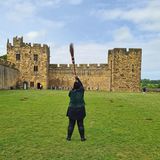 Alnwick Castle, eine Burg, in deren Hof jemand einen Besen hält. Hier findet das Flugtraining im "Harry Potter"-Film statt
