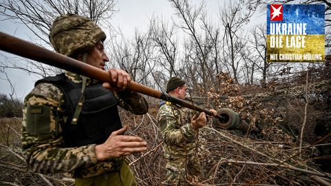 Zwei Soldaten der ukrainischen Streitkräfte reinigen das Rohr einer getarnten selbstfahrenden Panzerhaubitze