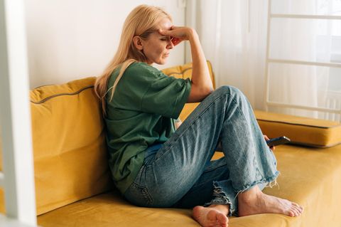 Frau mit intrusiven Gedanlen sitzt auf einem Sofa