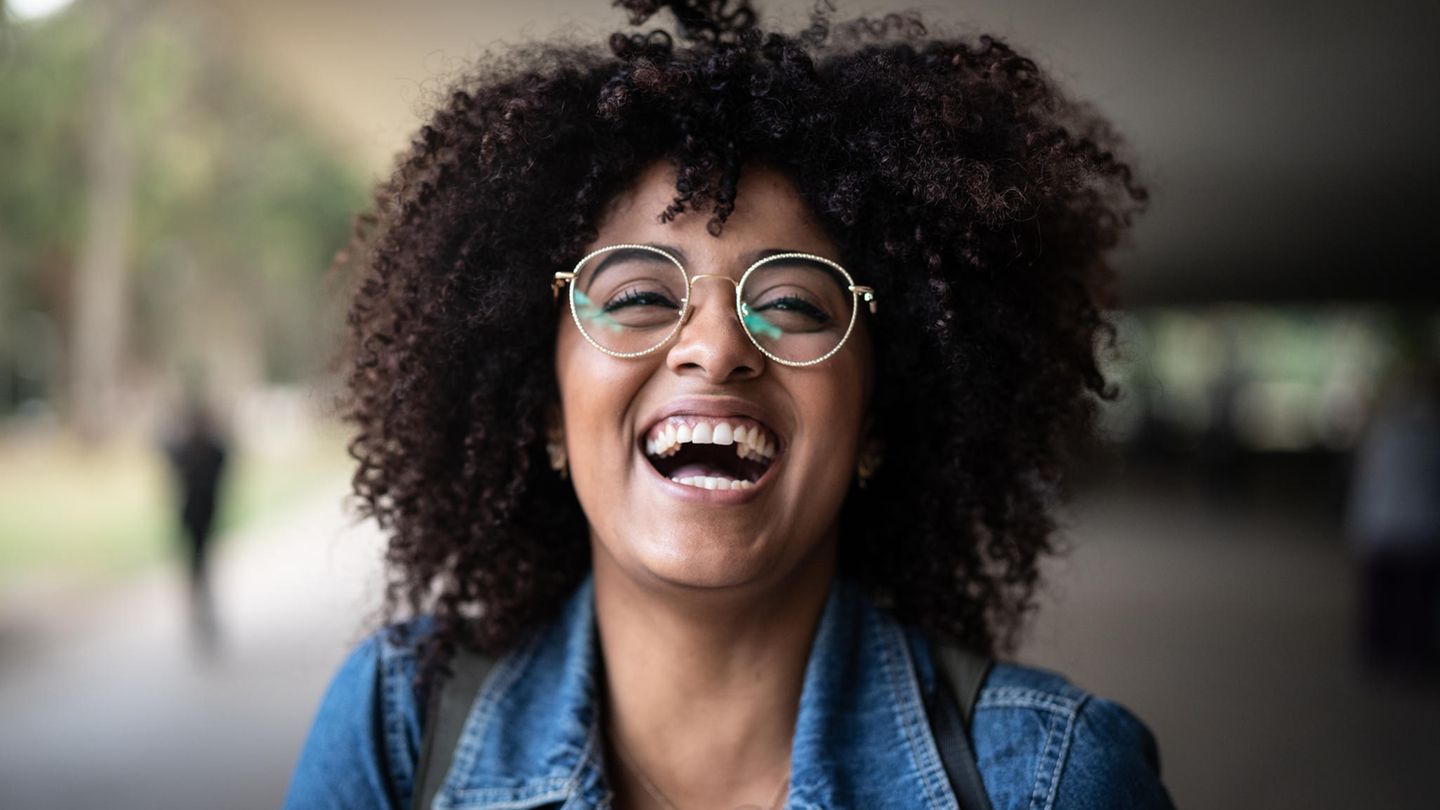 Frau mit Brille lacht fröhlich in die Kamera