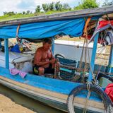 Fast auf dem Trockenen: Ein Fischer sitzt neben einem Kühlschrank in seinem Boot und flickt ein Netz. Rausfahren und fischen ist unmöglich, dafür sind die Gewässer nicht mehr tief genug. Die Pegelstände einiger der wichtigsten Flüsse waren zuletzt in noch nie da gewesenem Maße gesunken.