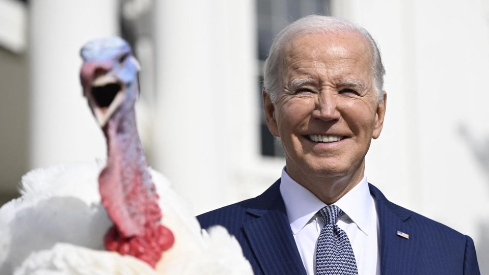 Ein Truthahn mit geöffnetem Schnabel sitzt auf einem Podest vor US-Präsident Joe Biden und dem Weißen Haus
