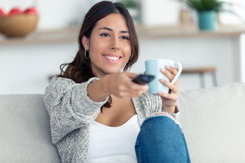 Frau sitzt vor einem Fernseher