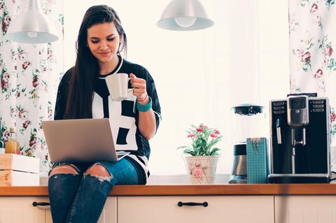 Frau sitzt neben Kaffeemaschine