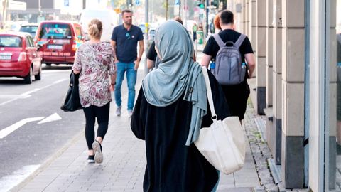 Eine Muslima läuft auf der Straße, von hinten zu sehen