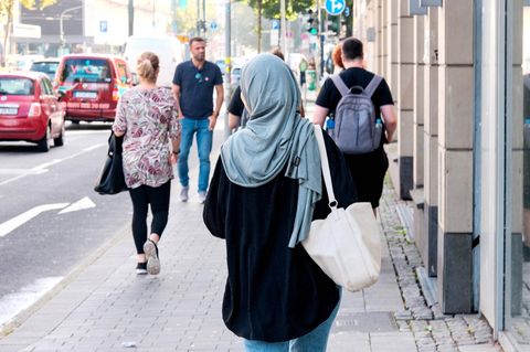 Eine Muslima läuft auf der Straße, von hinten zu sehen