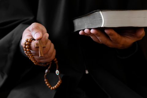 Exorzismus: Ein Priester hält ein Kreuz und eine Bibel in der Hand