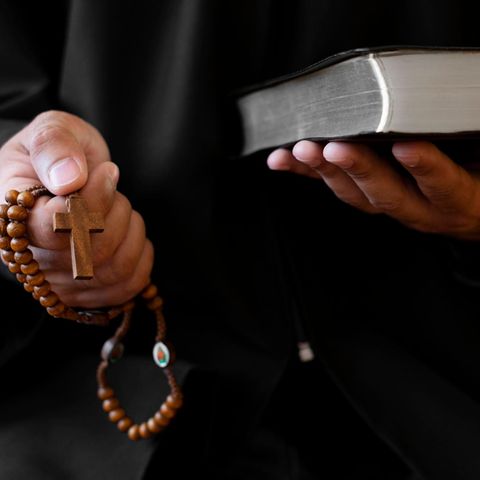 Exorzismus: Ein Priester hält ein Kreuz und eine Bibel in der Hand