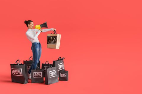 Eine junge Frau, die draußen am Telefon SMS schreibt.