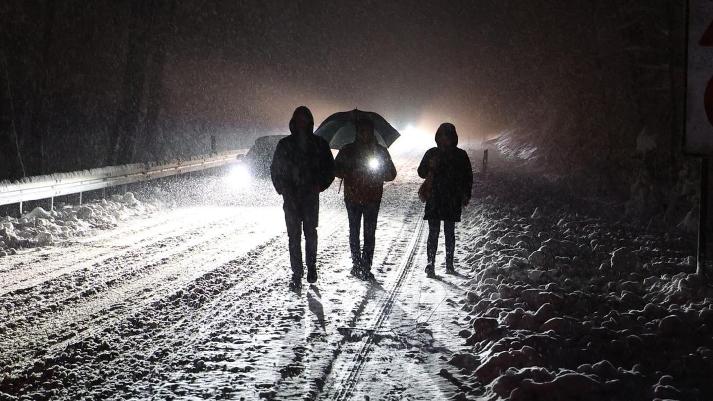 Menschen gehen nachts auf einer verschneiten Straße