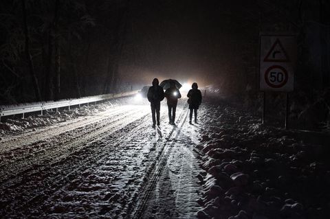 Menschen gehen nachts auf einer verschneiten Straße