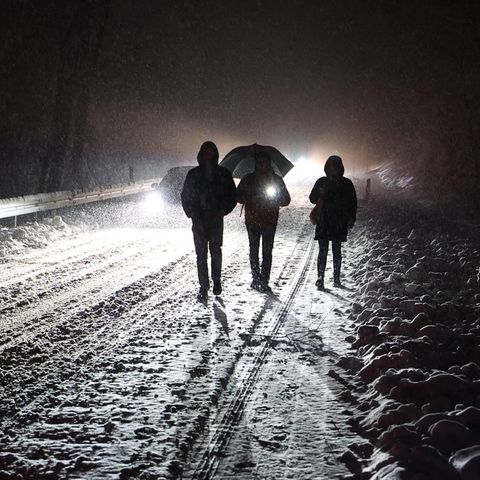 Menschen gehen nachts auf einer verschneiten Straße
