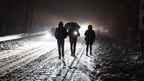 Menschen gehen nachts auf einer verschneiten Straße