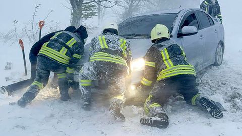 Ukrainische Rettungskräfte versuchen, ein im Schnee steckengebliebenes Auto auf der Autobahn in der Region Odessa zu schieben