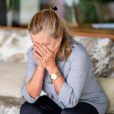 Eine Frau bedeckt ihr Gesicht mit den Händen