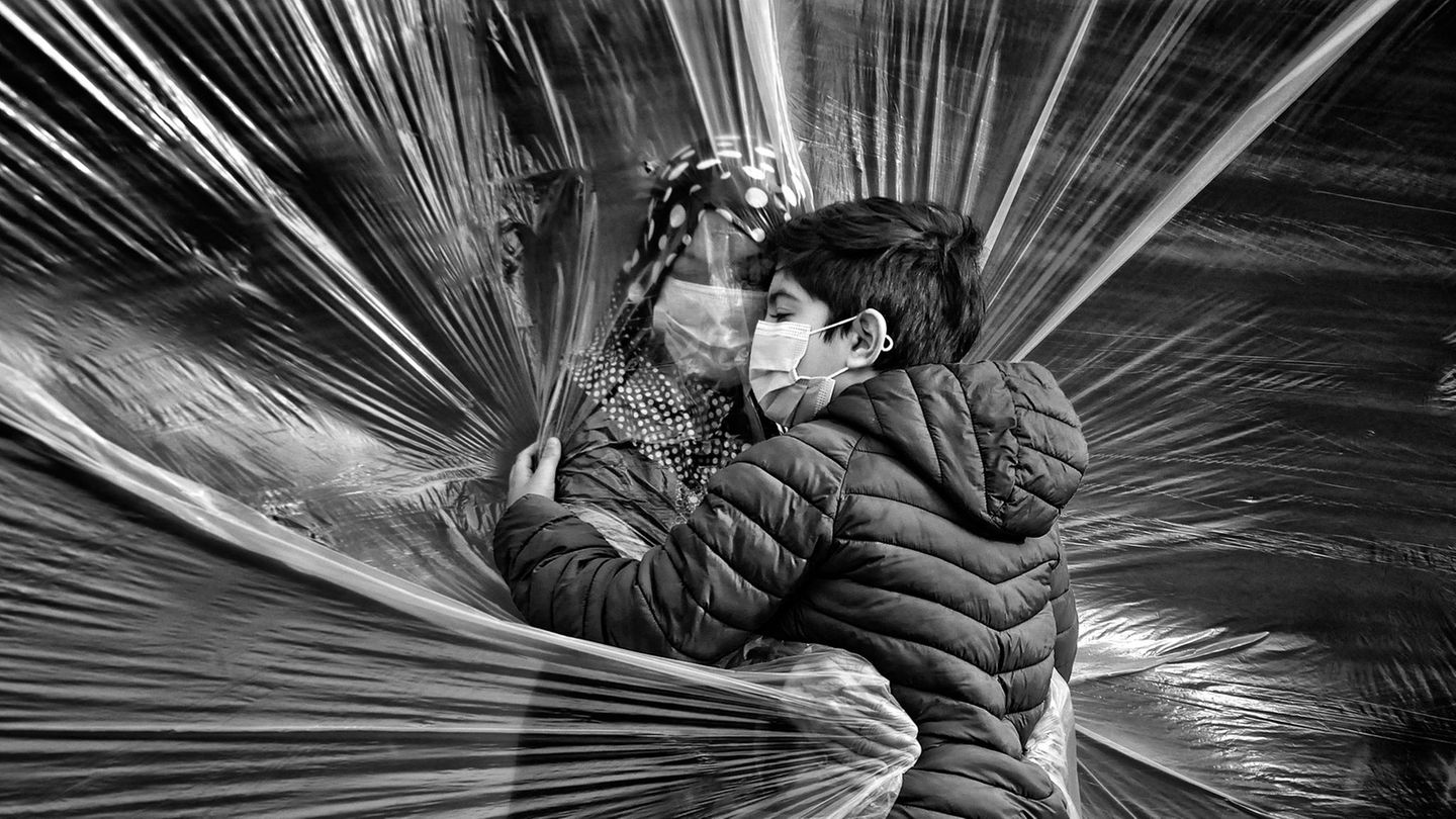 Ein Junge und seine Großmutter schließen sich durch eine Folie in die Arme