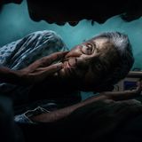 Ein junger Mensch berührt sanft das Gesicht eine alten Frau