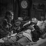 Eine Frau hält die Hand ihres Mannes, der im Sterben liegt