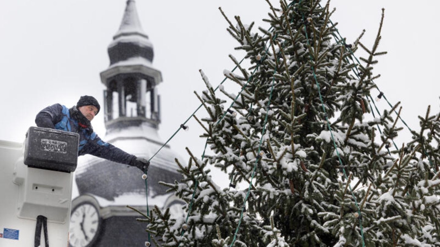 Ilmenau, Thüringen. Pünktlich zum 1. Advent sorgt der Wintereinbruch neben Chaos auch für weihnachtliche Stimmung. Hier installiert Elektriker Axel Möller die Beleuchtung an einem verschneiten Weihnachtsbaum im Stadtzentrum.