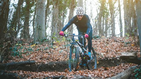 Radmode für Männer: Mountainbiker im Spätherbst in einem Waldstück