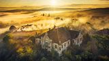 Eine in gelbes Licht getauchte Wolkenlandschaft über alten Gebäuden