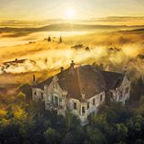 Eine in gelbes Licht getauchte Wolkenlandschaft über alten Gebäuden