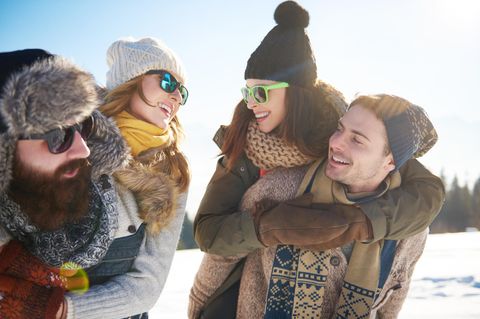 Wintermützen Trends: Zwei Pärchen im Schnee mit verschiedenen Mützen