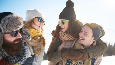 Wintermützen Trends: Zwei Pärchen im Schnee mit verschiedenen Mützen