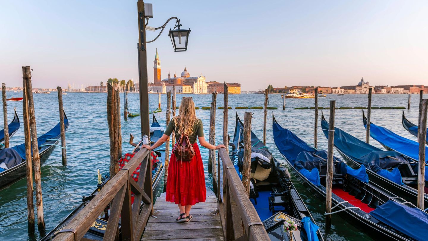 Frau in rotem Rock blickt auf Venedig