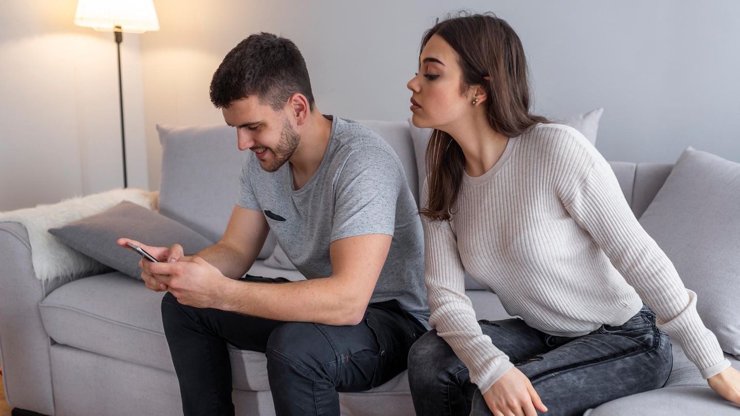 Frau schaut Mann auf Smartphone Whatsapp