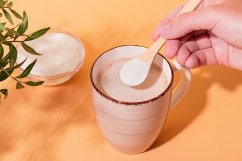 Person gibt Kollagenpulver in seinen Glow Coffee