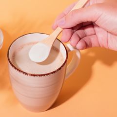 Person gibt Kollagenpulver in seinen Glow Coffee