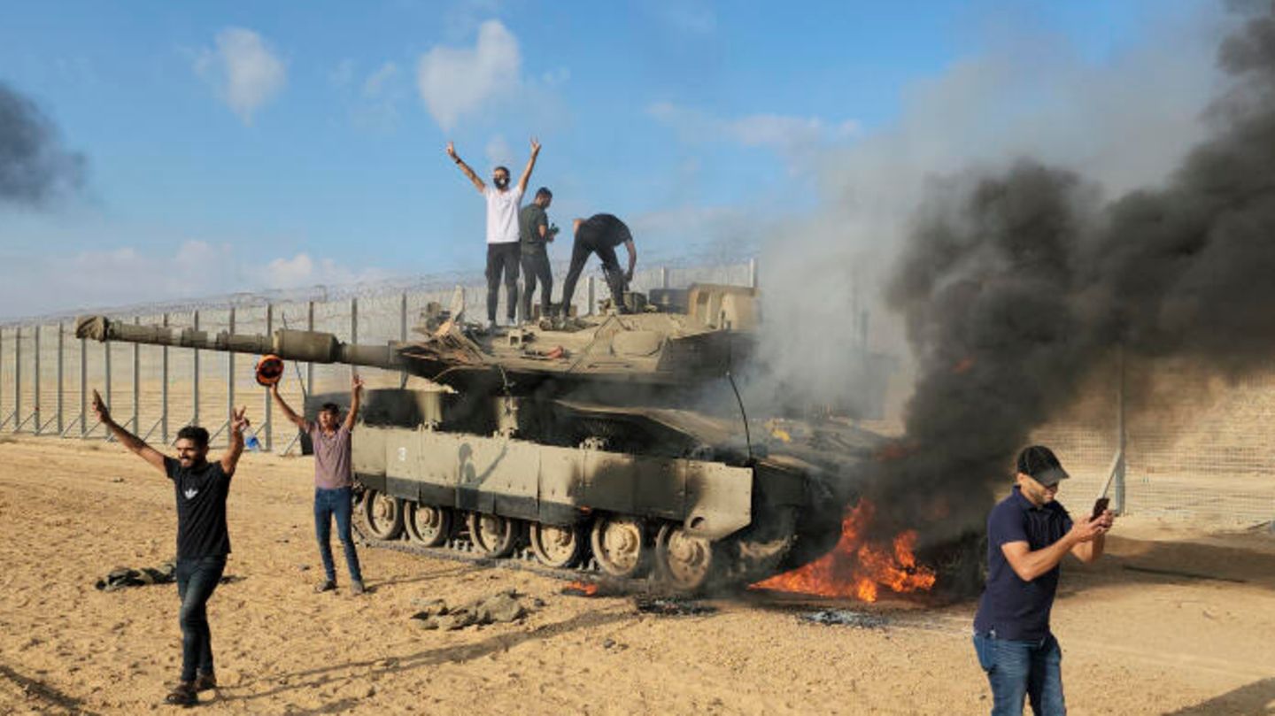 Palästinenser feiern am 7. Oktober an einem zerstörten israelischen Panzer