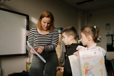 Eine Lehrerin erklärt zwei Kindern eine Aufgabe in der Klasse