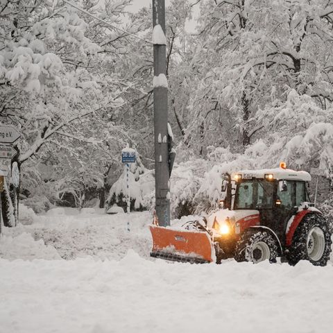 Ein Räumfahrzeug beseitigt Schneemassen auf einem Parkplatz in München