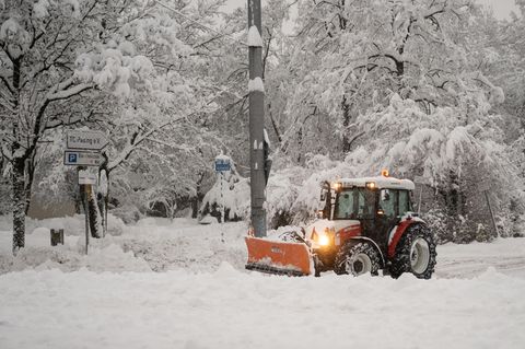 Ein Räumfahrzeug beseitigt Schneemassen auf einem Parkplatz in München