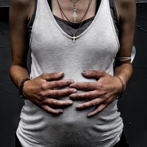 Der Bauch einer Schwangeren in einem weißen Tanktop