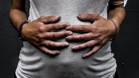 Der Bauch einer Schwangeren in einem weißen Tanktop