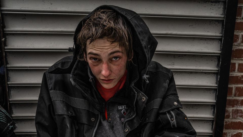 Ein junger Mann blickt verzweifelt unter einer großen Kapuze hervor