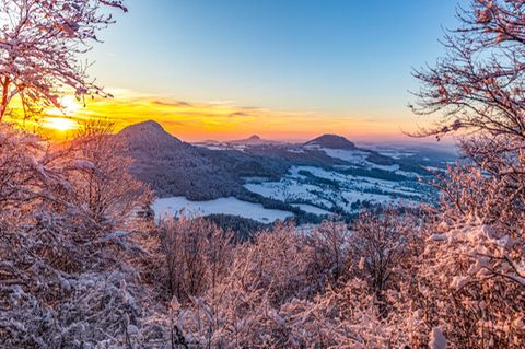 Die Sonne geht hinter den drei Kaiserbergen nahe Hornberg in Baden-Württemberg unter. Willkommen im Winterwunderland!
