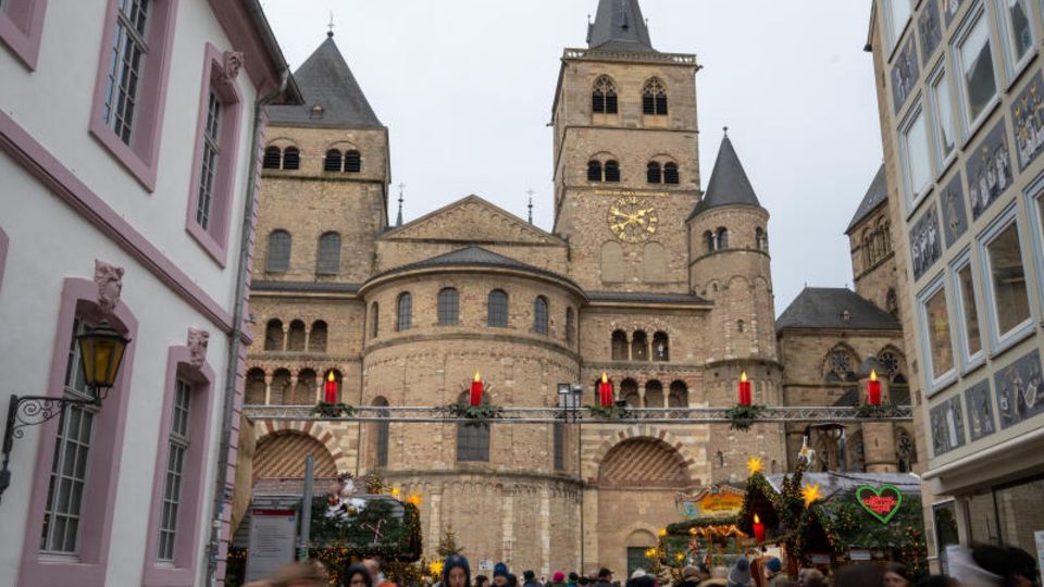 Menschen gehen von und zum Weihnachtsmarkt am Dom in Trier