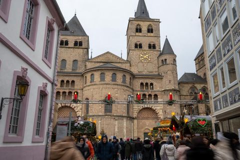 Menschen gehen von und zum Weihnachtsmarkt am Dom in Trier